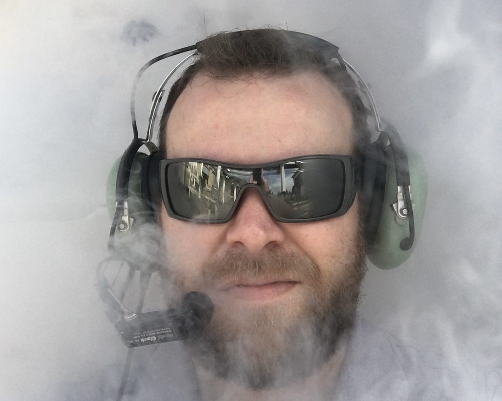 Ben Henderson in sunglasses and a headset, surrounded by white vapor