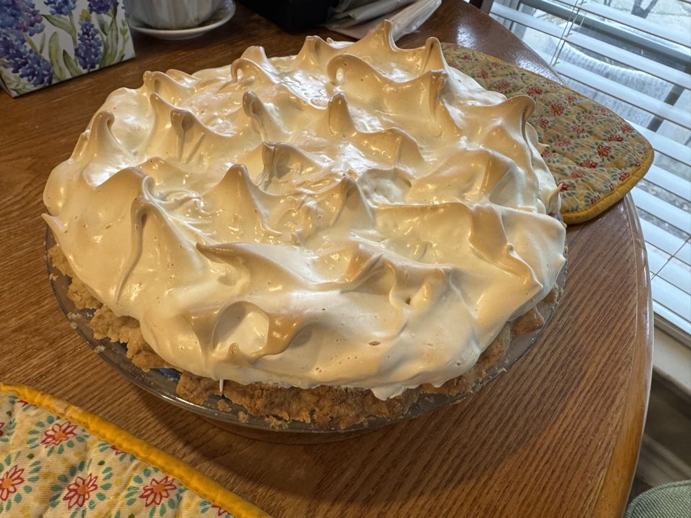 Chocolate pie topped with browned meringue peaks on a wooden table
