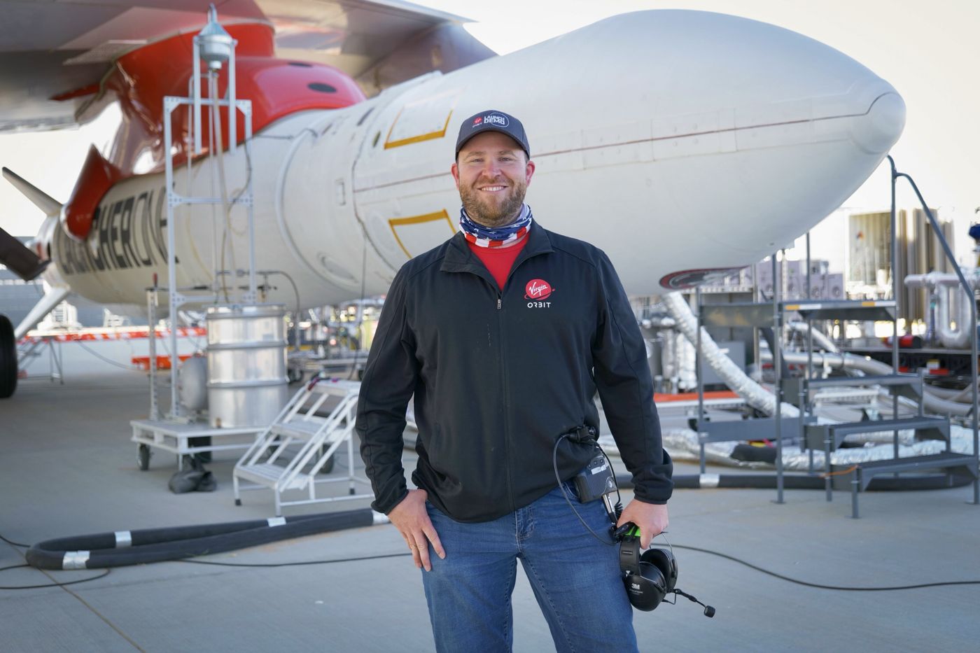 Ben Henderson standing in front of the LauncherOne rocket mounted under the wing of a 747
